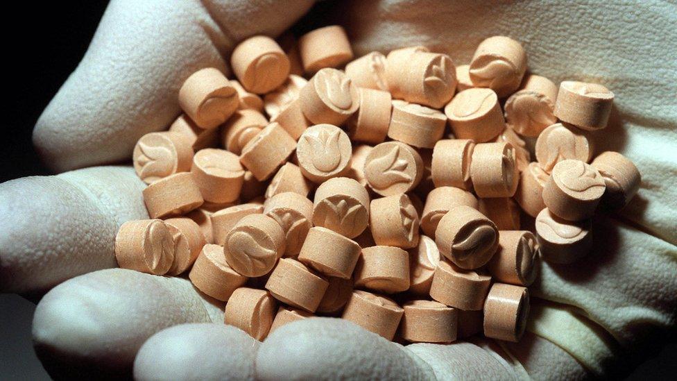 Person examining MDMA with gloves in a controlled environment.